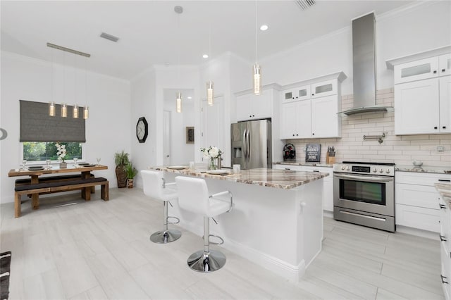 kitchen featuring a center island with sink, wall chimney exhaust hood, white cabinets, and stainless steel appliances