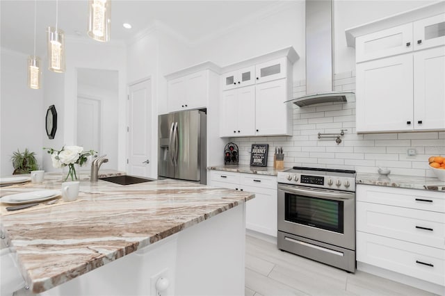 kitchen featuring appliances with stainless steel finishes, tasteful backsplash, wall chimney exhaust hood, decorative light fixtures, and white cabinets