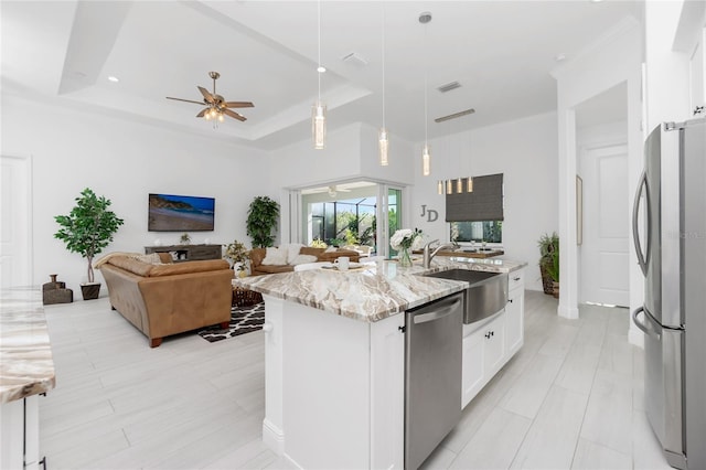 kitchen featuring white cabinetry, stainless steel appliances, a raised ceiling, pendant lighting, and a kitchen island with sink