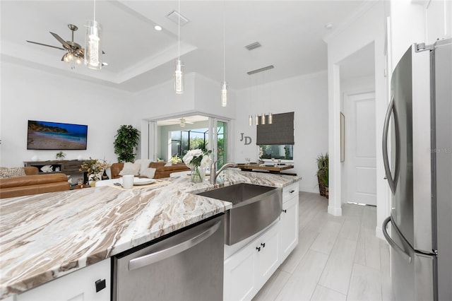 kitchen featuring white cabinets, sink, appliances with stainless steel finishes, decorative light fixtures, and light stone counters