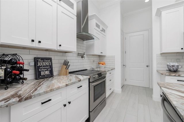 kitchen featuring white cabinets, wall chimney range hood, and stainless steel appliances