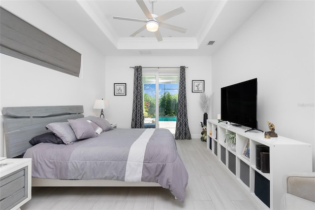 bedroom featuring a raised ceiling, light hardwood / wood-style flooring, ceiling fan, access to exterior, and ornamental molding