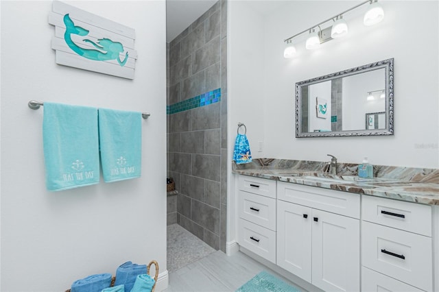 bathroom featuring a tile shower and vanity