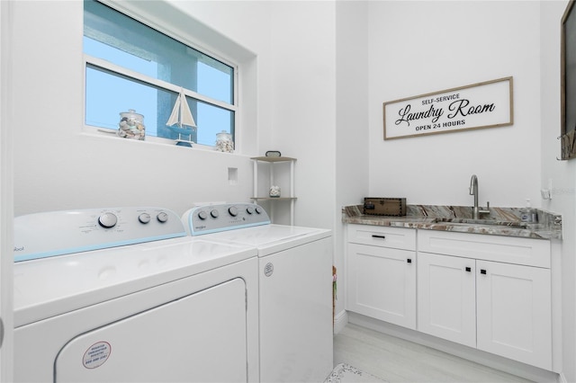 washroom with cabinets, washing machine and dryer, light wood-type flooring, and sink