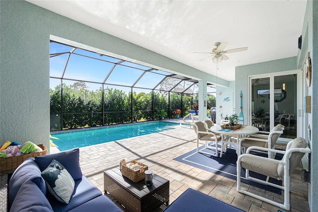 view of swimming pool featuring outdoor lounge area, ceiling fan, a patio, and glass enclosure