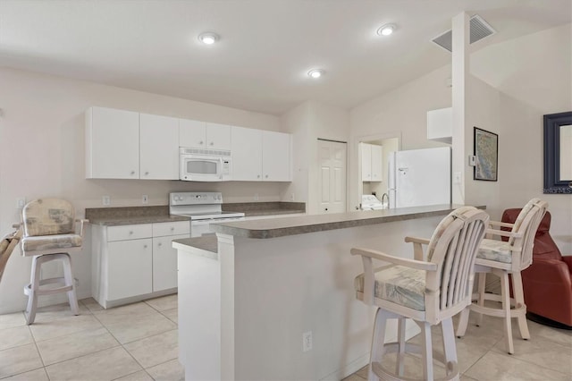 kitchen featuring kitchen peninsula, a kitchen bar, white appliances, white cabinets, and lofted ceiling