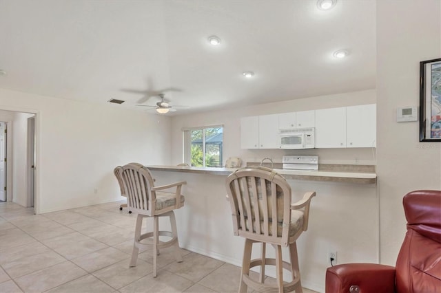 kitchen with white cabinets, a kitchen breakfast bar, white appliances, and ceiling fan