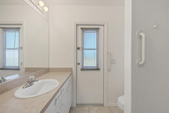 bathroom with tile patterned flooring, vanity, toilet, and a wealth of natural light