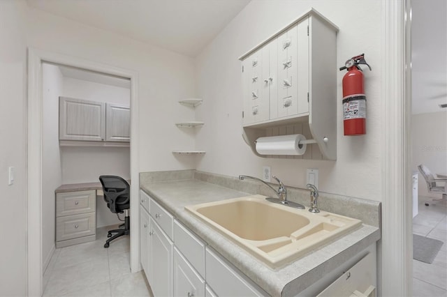 kitchen with light tile patterned floors, white cabinetry, and sink