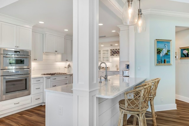 kitchen featuring tasteful backsplash, white cabinets, stainless steel appliances, and ornamental molding