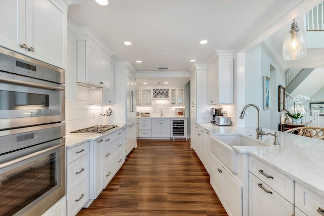 kitchen featuring backsplash, white cabinets, sink, wine cooler, and appliances with stainless steel finishes