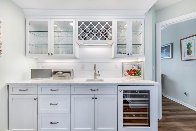 bar with light stone countertops, dark hardwood / wood-style flooring, beverage cooler, sink, and white cabinets