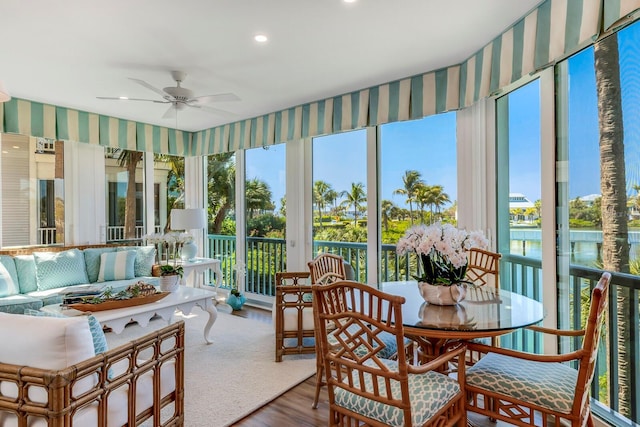 sunroom with ceiling fan, a healthy amount of sunlight, and a water view