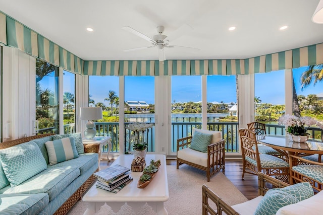 sunroom / solarium featuring plenty of natural light, ceiling fan, and a water view