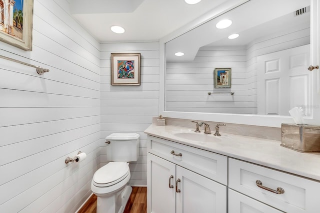 bathroom with vanity, wood walls, toilet, and wood-type flooring