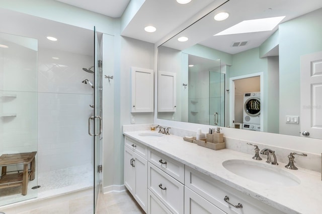 bathroom with vanity, a skylight, tile patterned flooring, stacked washing maching and dryer, and a shower with shower door