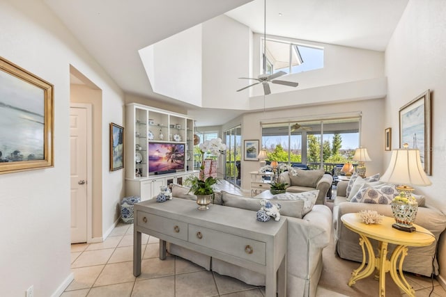 living room featuring ceiling fan, light tile patterned floors, and a towering ceiling