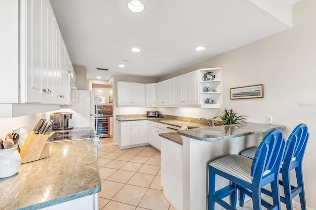 kitchen with kitchen peninsula, light tile patterned floors, white cabinetry, and a breakfast bar area