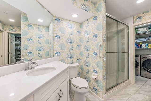 bathroom featuring vanity, toilet, an enclosed shower, and washing machine and clothes dryer