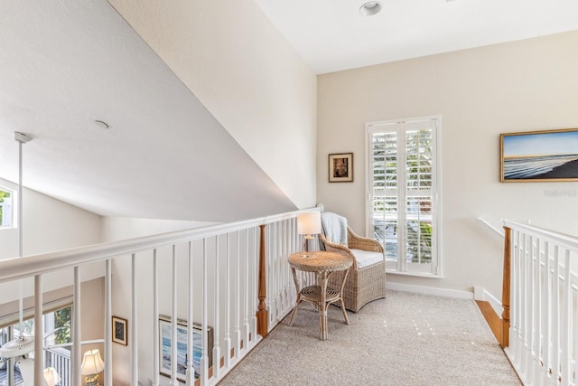 hallway featuring carpet floors, a healthy amount of sunlight, and vaulted ceiling