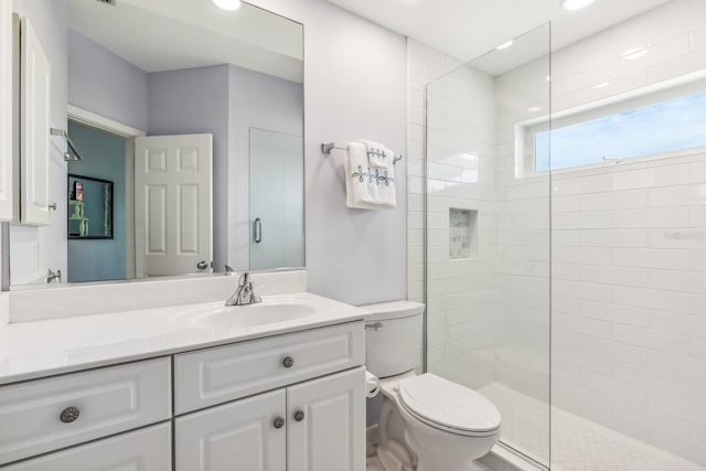 bathroom with toilet, vanity, and tiled shower