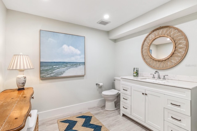 bathroom with wood-type flooring, vanity, and toilet