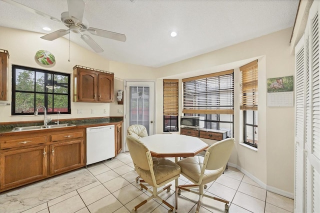 kitchen featuring a textured ceiling, ceiling fan, sink, light tile patterned floors, and dishwasher