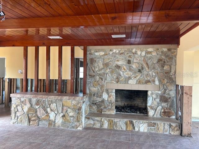 room details with beam ceiling, wood ceiling, and a stone fireplace