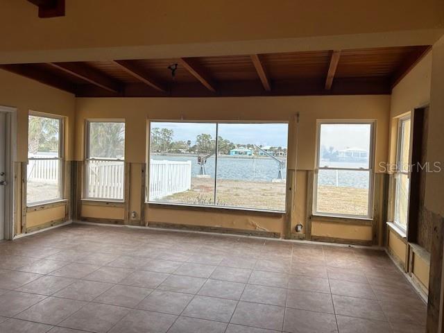 unfurnished sunroom with wood ceiling, a water view, and beam ceiling