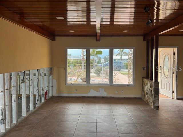 unfurnished room featuring wooden ceiling, light tile patterned floors, and beam ceiling