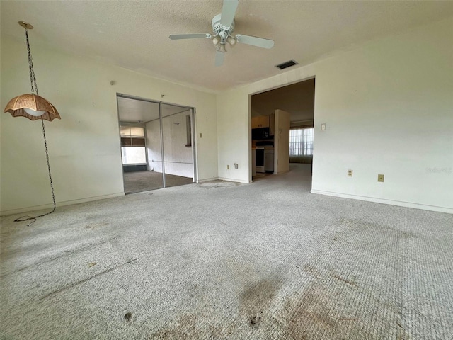 unfurnished bedroom with carpet, ceiling fan, a textured ceiling, and a closet