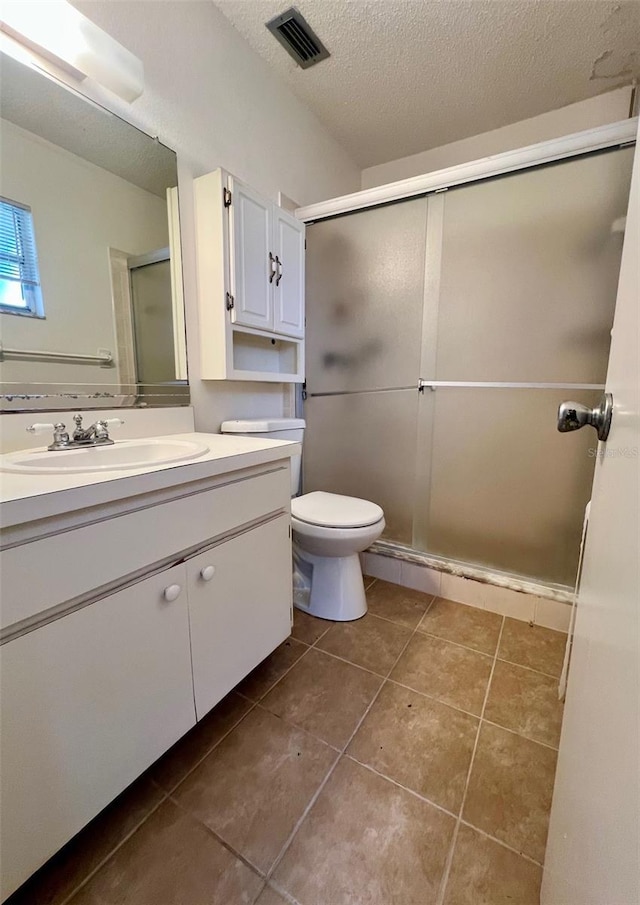 bathroom featuring vanity, tile patterned flooring, toilet, a textured ceiling, and walk in shower