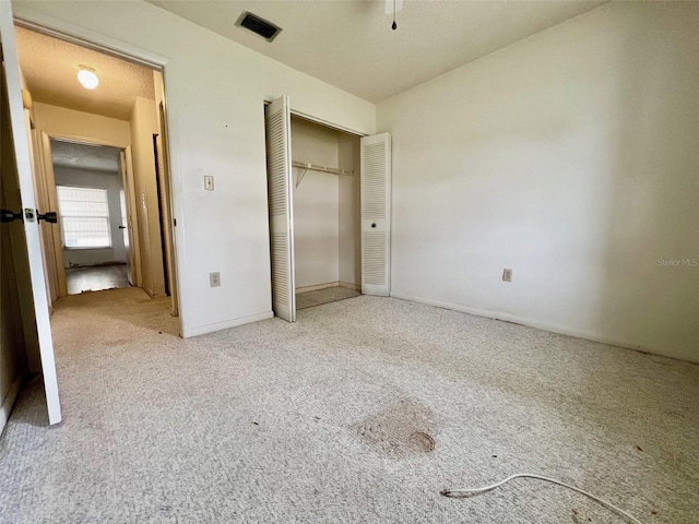 unfurnished bedroom featuring light carpet and a closet