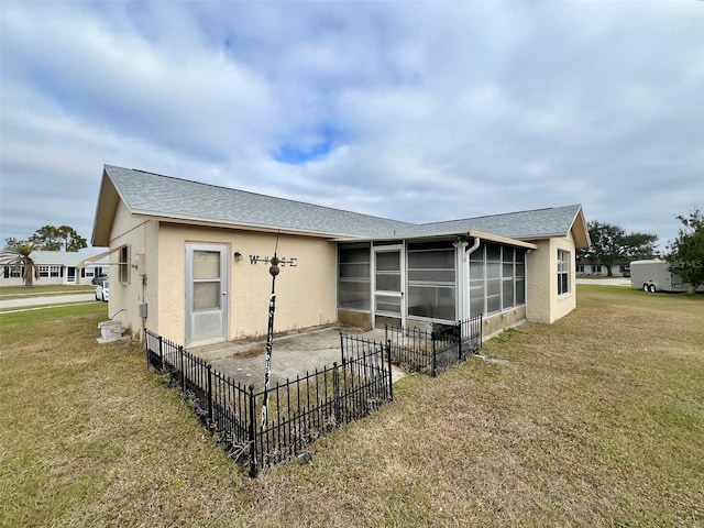 rear view of house featuring a sunroom and a yard