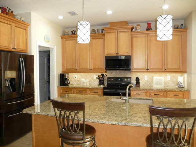 kitchen featuring appliances with stainless steel finishes, a breakfast bar, sink, pendant lighting, and an island with sink