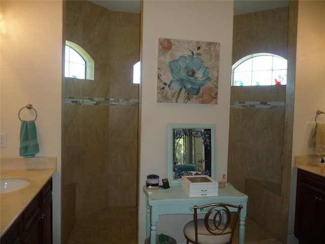 bathroom featuring a wealth of natural light, vanity, and tiled shower