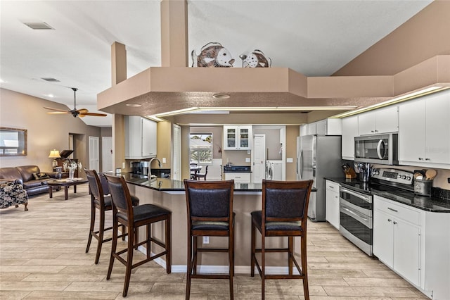 kitchen featuring independent washer and dryer, stainless steel appliances, white cabinetry, and ceiling fan