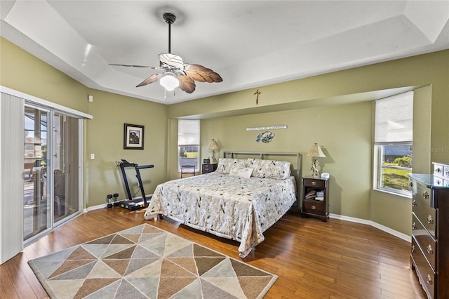 bedroom featuring access to exterior, ceiling fan, a raised ceiling, and multiple windows