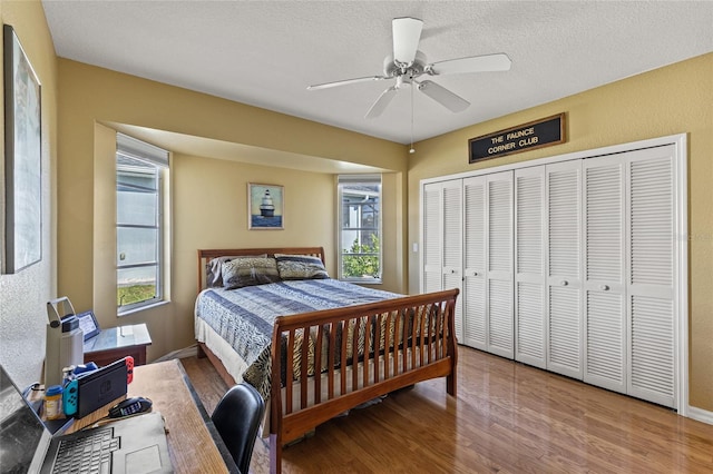 bedroom with multiple windows, hardwood / wood-style floors, a closet, and ceiling fan