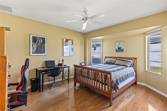 bedroom featuring ceiling fan, wood-type flooring, and a textured ceiling