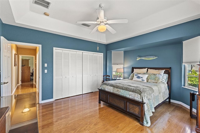 bedroom featuring hardwood / wood-style flooring, ceiling fan, a raised ceiling, and a closet