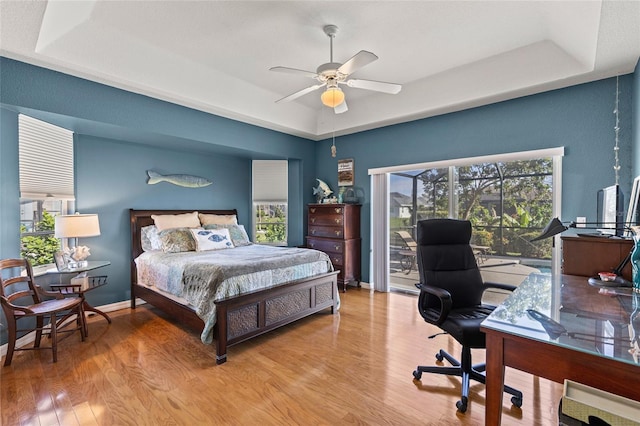 bedroom with a raised ceiling, ceiling fan, and light hardwood / wood-style floors