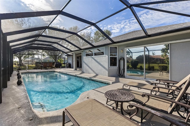 view of swimming pool featuring glass enclosure and a patio area