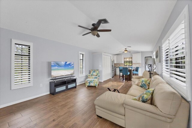 living room with ceiling fan, a healthy amount of sunlight, and lofted ceiling