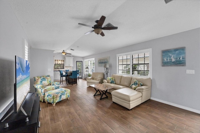 living room with a textured ceiling, vaulted ceiling, and ceiling fan