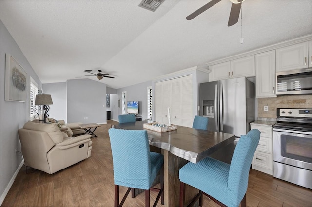 dining area featuring ceiling fan, dark hardwood / wood-style flooring, and vaulted ceiling