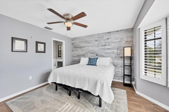 bedroom featuring wooden walls, ceiling fan, and a textured ceiling