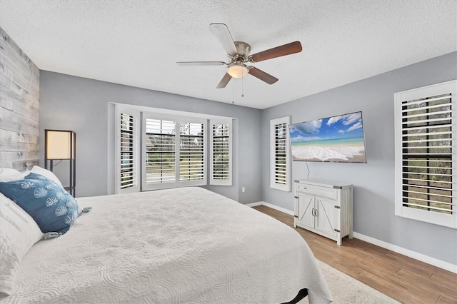 bedroom featuring ceiling fan, a textured ceiling, and light wood-type flooring