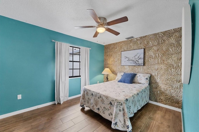 bedroom with ceiling fan, dark wood-type flooring, and a textured ceiling