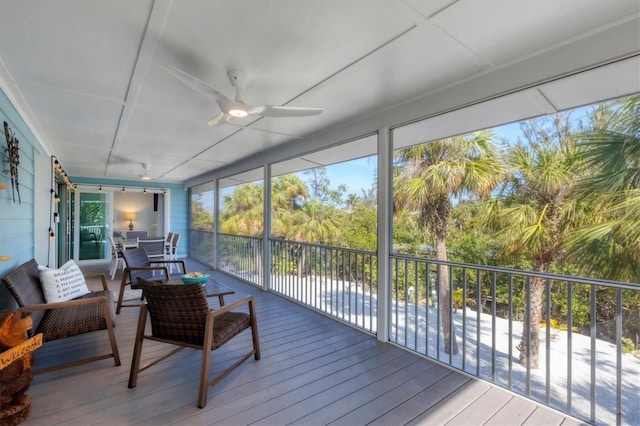 sunroom with ceiling fan and a water view